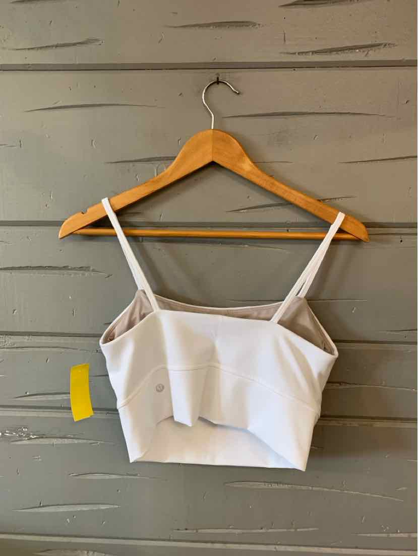 White cropped tank top with thin adjustable straps, square neckline, and fitted silhouette on wooden hanger.
