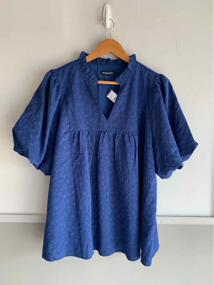 Blue short-sleeve blouse with subtle textured pattern and V-neck on wooden hanger.