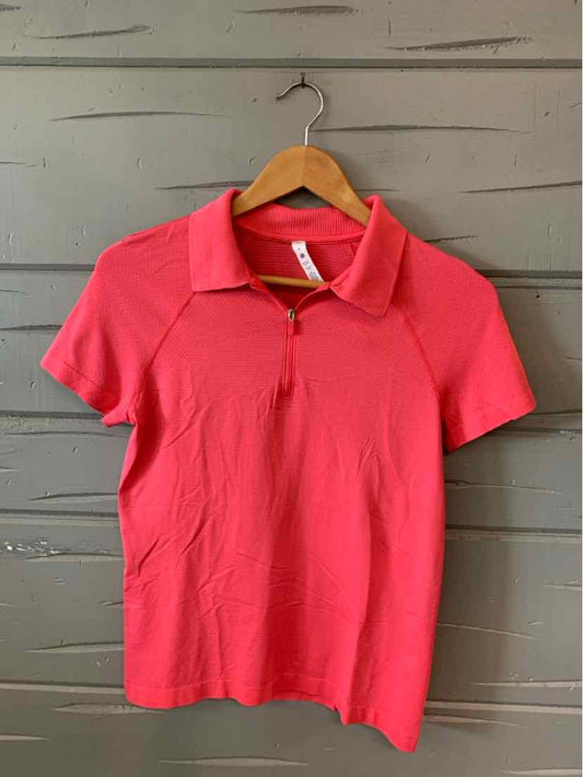 Pink short-sleeve polo shirt with front zipper and collar on wooden hanger.
