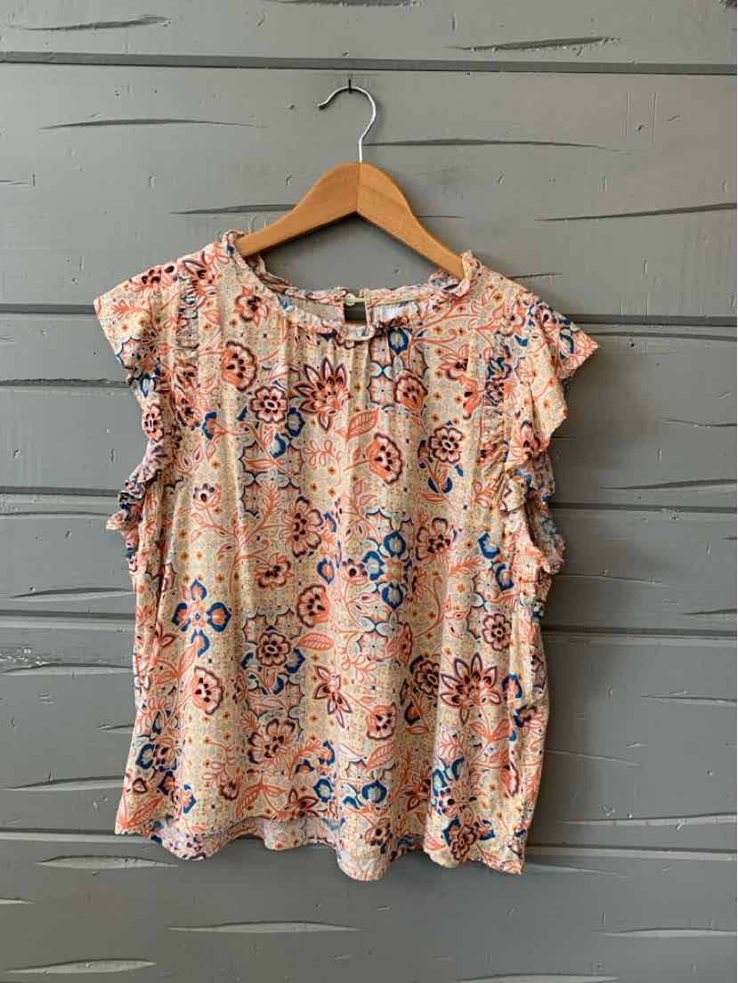 Orange floral sleeveless blouse with ruffled trim and round neckline on wooden hanger.
