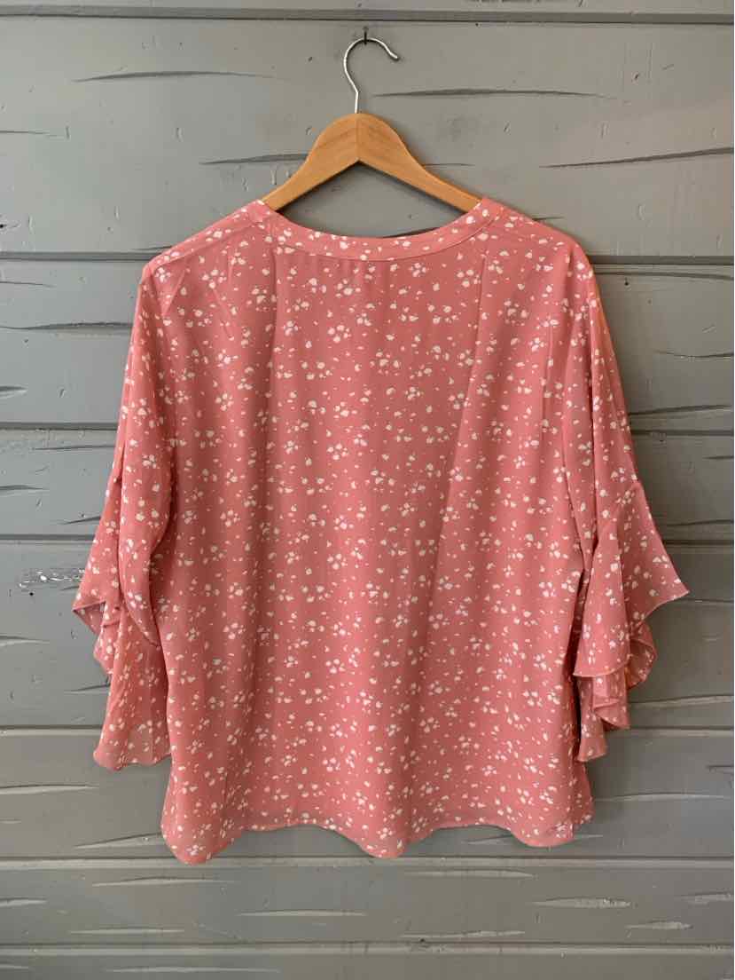 Pink blouse with white floral pattern and tiered ruffle sleeves, size XL, hanging on wooden hanger.
