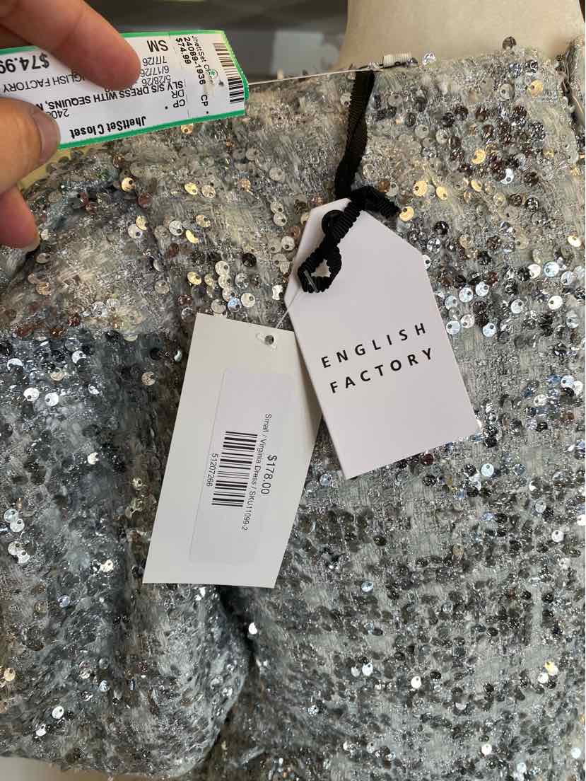 Silver sequin fabric with English Factory and barcode tags attached by black string.
