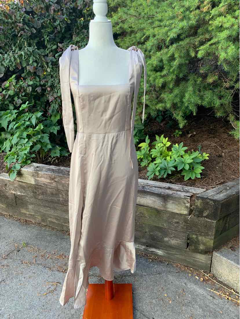 Beige sleeveless midi dress with square neckline and flowy skirt on mannequin outdoors.