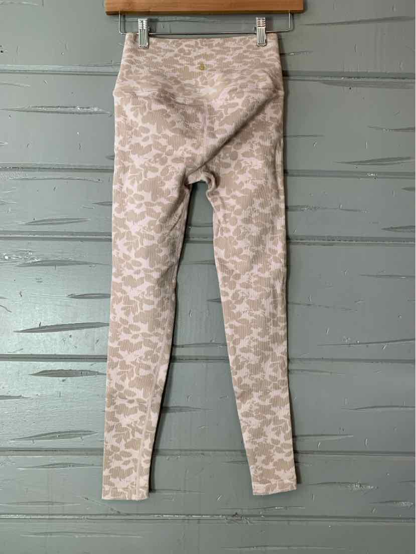 Light beige floral patterned leggings with slim fit and soft fabric hanging on wooden hanger.