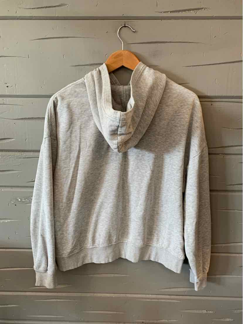 Light gray cropped hoodie with long sleeves and a relaxed fit hanging on a wooden hanger.