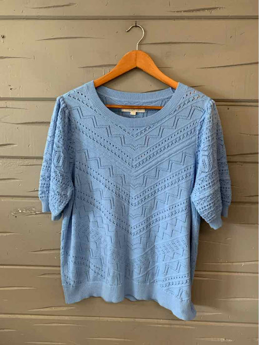 Light blue knitted short-sleeve sweater with chevron and lace patterns on wooden hanger.