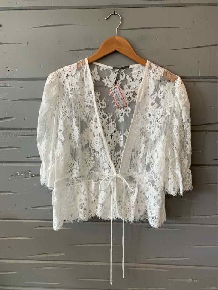 White lace blouse with three-quarter ruffled sleeves, V-neck, and tie front closure.