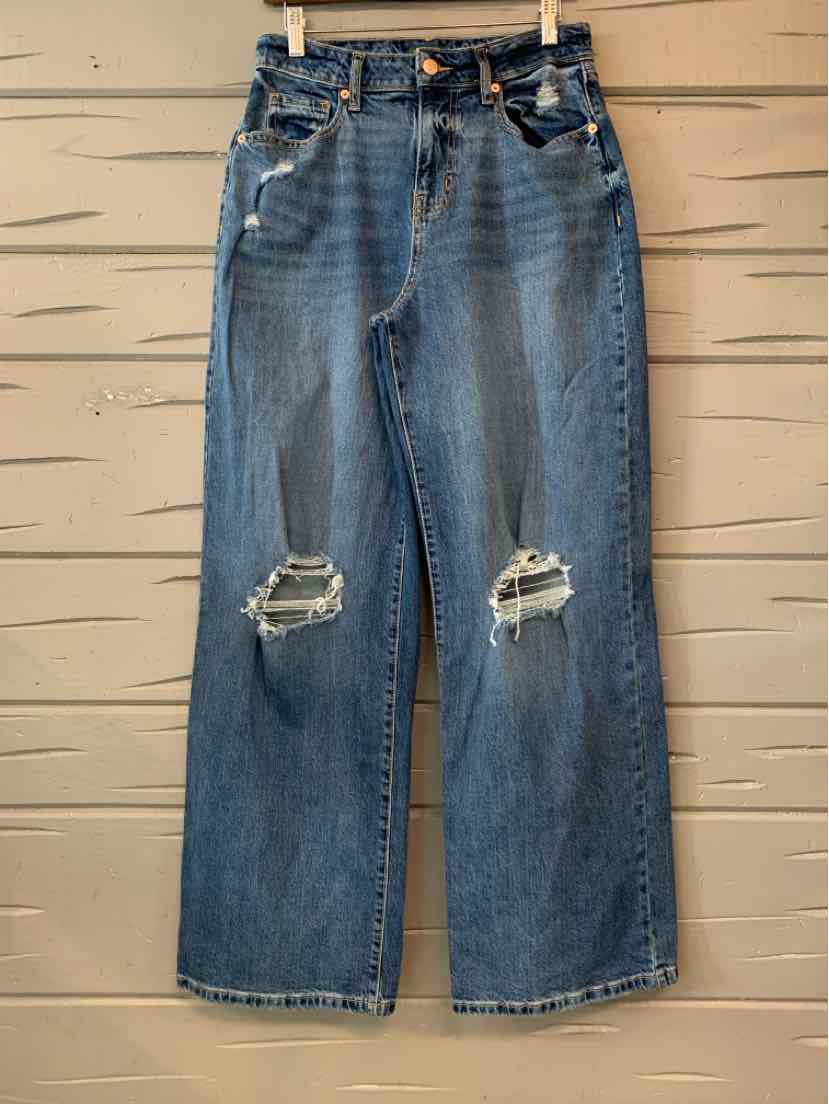 Blue denim wide-leg jeans with a high waist, belt loops, and distressed patches at both knees.