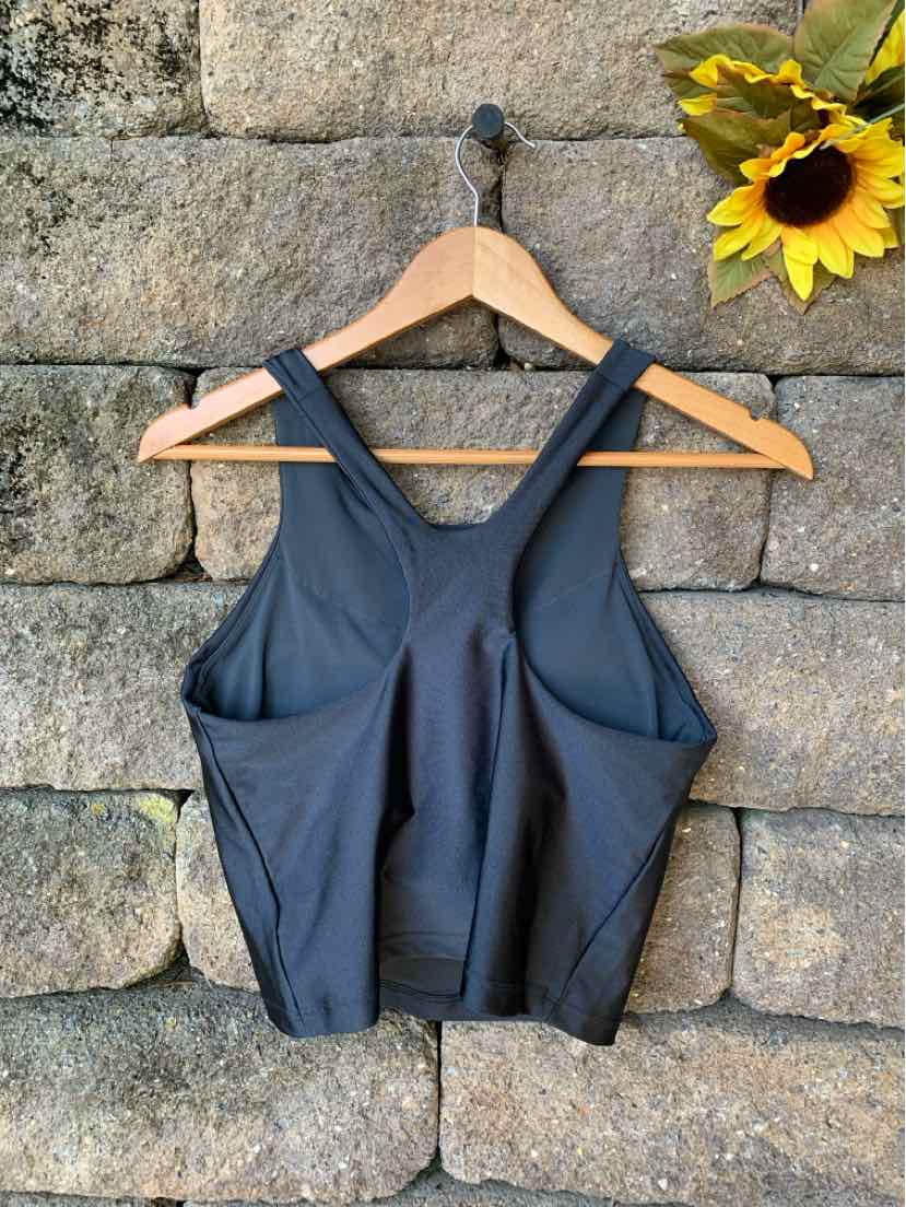 Black sleeveless athletic crop top with thick straps and a fitted, stretchy fabric hanging on a wooden hanger.