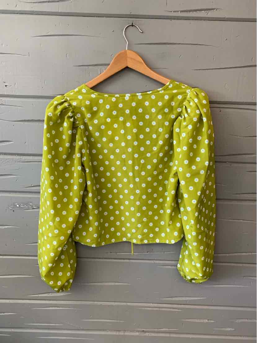 Green long-sleeve blouse with white polka dots and gathered puff shoulders on wooden hanger.
