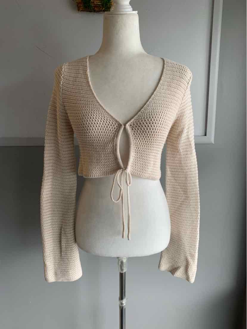 Light beige cropped knit cardigan with long sleeves and a deep V-neck that ties at the front.