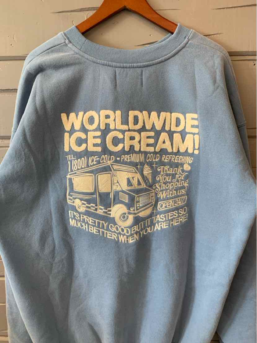 Blue oversized sweatshirt with cream-colored vintage-style Worldwide Ice Cream graphic and text on front.