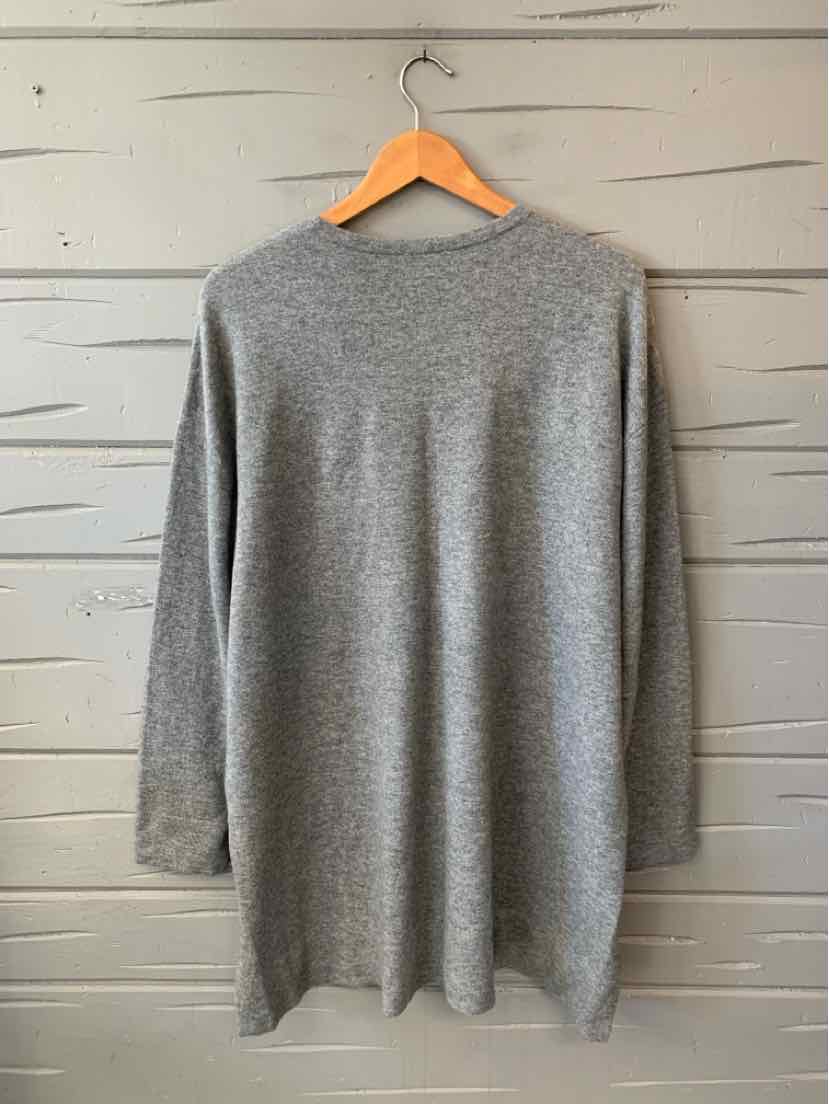 Gray cashmere long-sleeve sweater with a relaxed fit and straight hem, hanging on a wooden hanger.