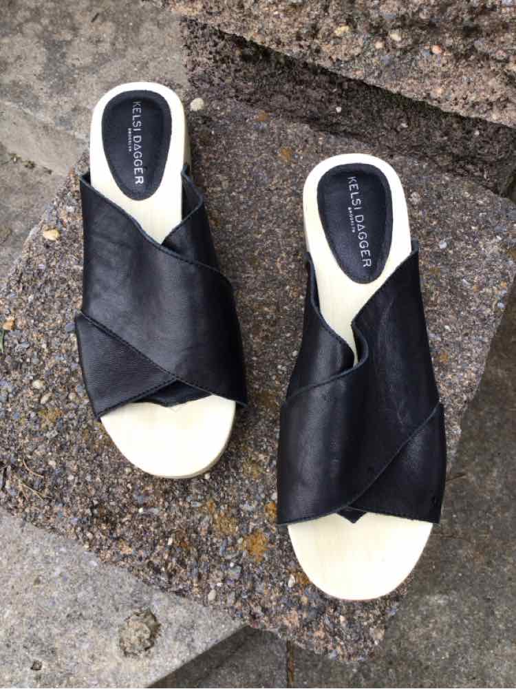 Women's black leather slip-on sandals with crossed straps and beige soles, size 6.5.