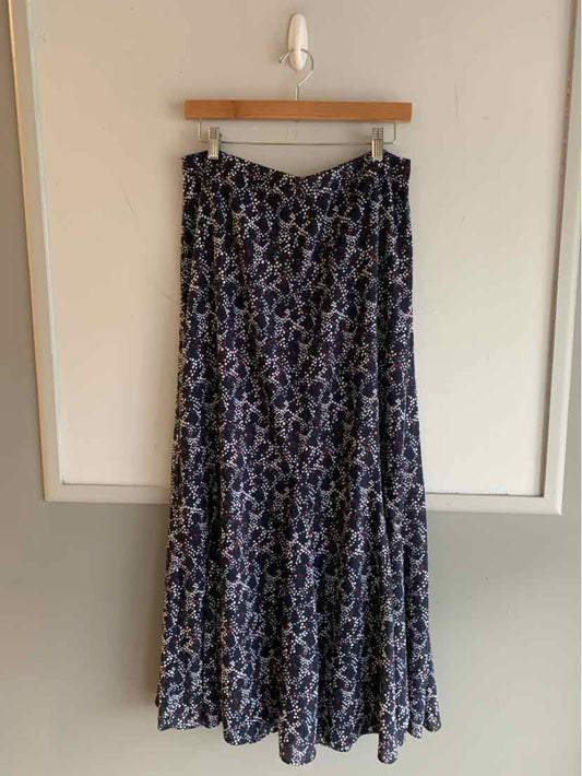 Black and white polka dot maxi skirt with flowy fabric and tiered hem hanging on wooden hanger.