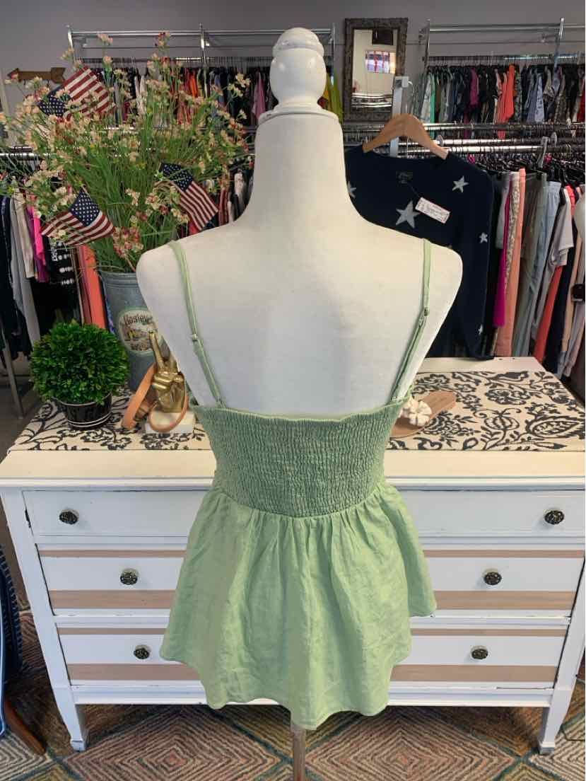 Light green sleeveless smocked top with peplum hem on white mannequin.