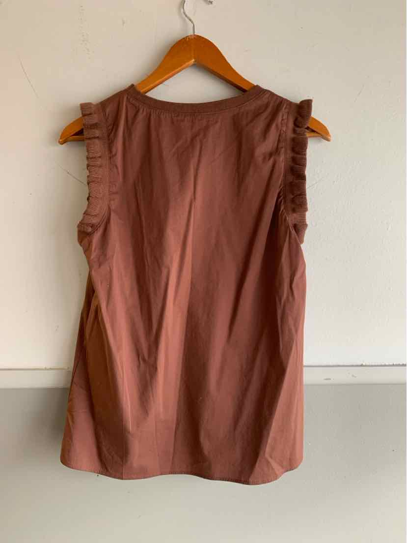 Brown sleeveless blouse with ruffled trim on shoulders, hanging on wooden hanger.