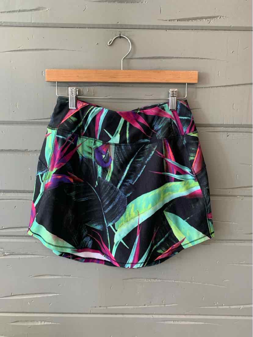 Black women’s shorts with vibrant neon green, pink, and blue abstract leaf pattern, size small, hanging on wooden hanger.