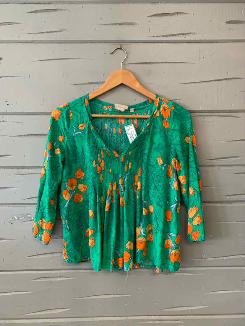 Green floral blouse with orange flowers, V-neck, and 3/4 sleeves on wooden hanger.