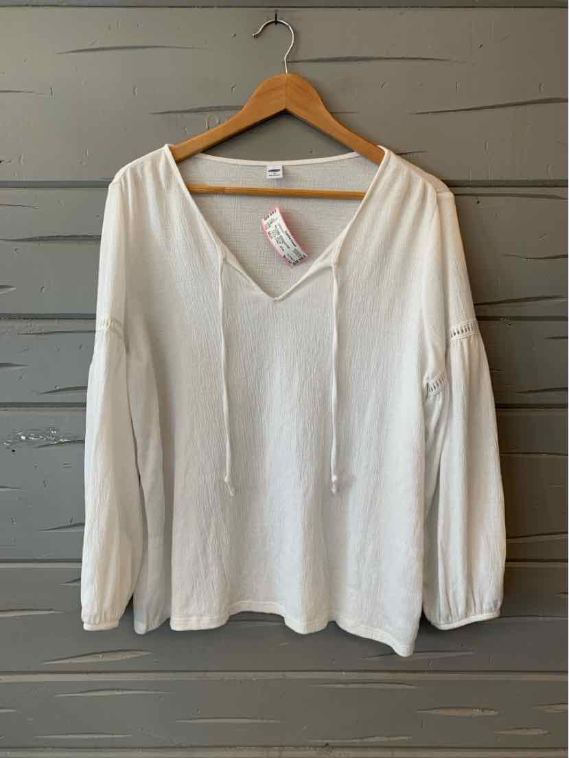 White long-sleeve V-neck blouse with drawstring ties and relaxed fit hanging on wooden hanger.