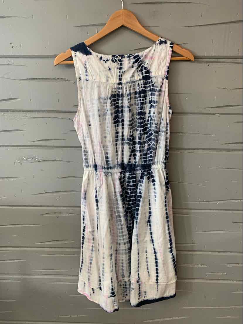Sleeveless white romper with navy blue tie-dye pattern and gathered waist on wooden hanger.