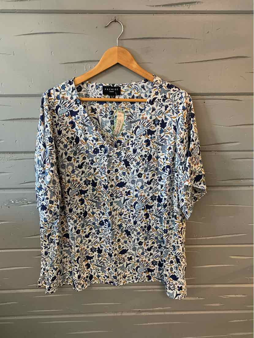 Blue and white floral print blouse with 3/4 sleeves and V-neck on wooden hanger.