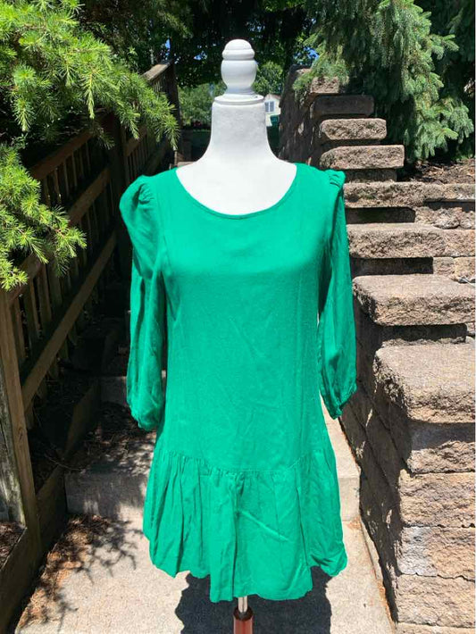 Green long-sleeve midi dress with a scoop neckline and ruffled hem on a mannequin outdoors.