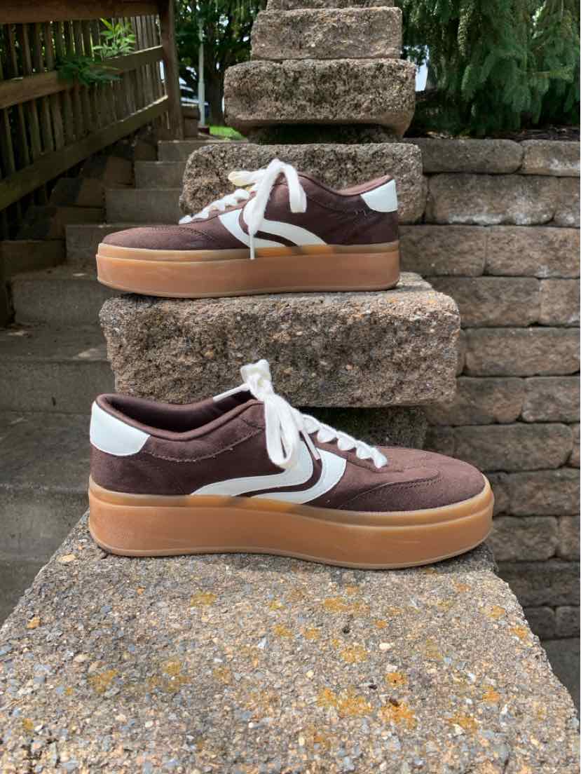 Brown suede low-top sneaker with white laces and beige rubber sole.