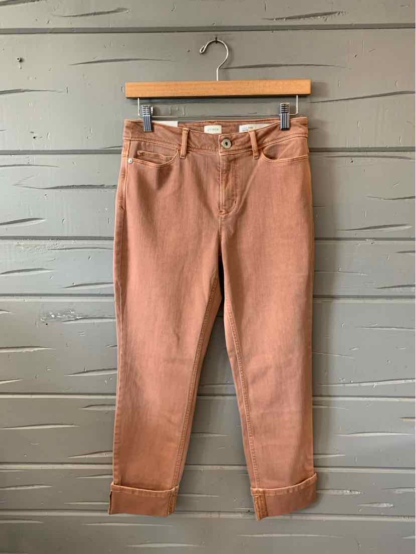 Light brown cropped denim jeans with front pockets and rolled cuffs hanging on wooden hanger.