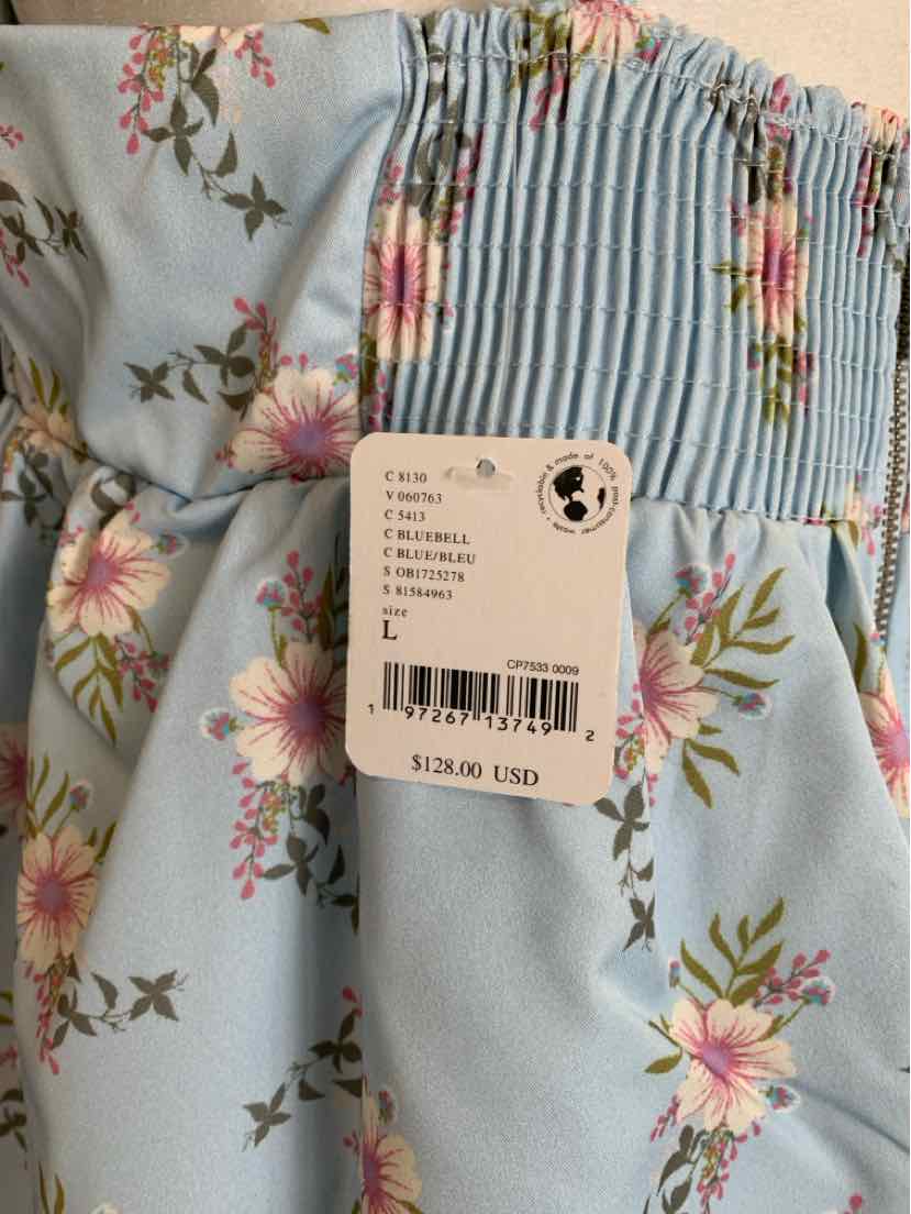Light blue floral dress with pink and white flowers, featuring mixed fabric patches and a price tag attached.