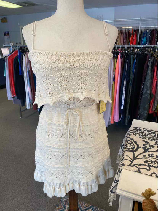 Cream crochet knit two-piece set with cropped tank and ruffled mini skirt.