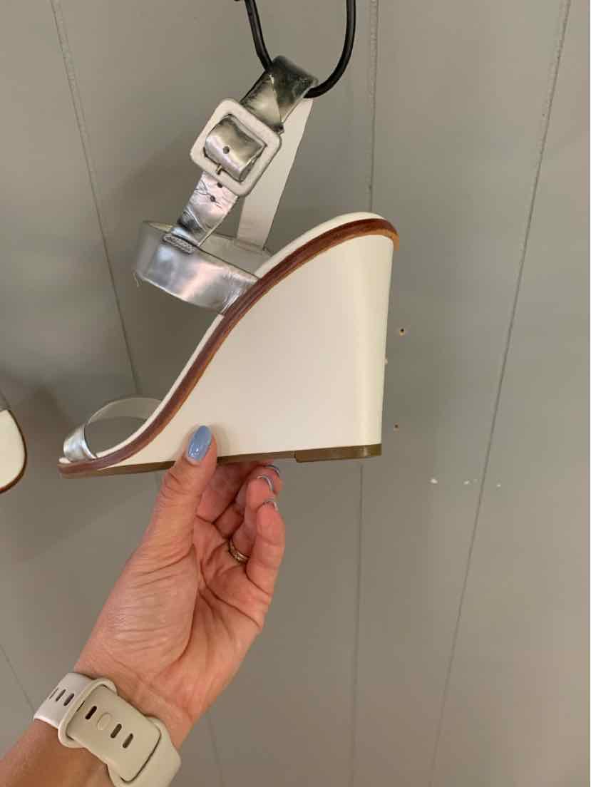 White wedge sandal with ankle strap and buckle, clear toe strap, and brown sole trim.