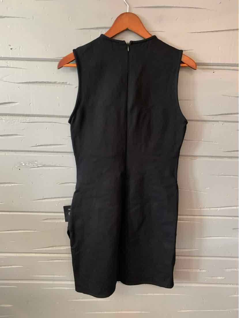 Sleeveless black fitted dress with high neckline and back zipper closure hanging on wooden hanger.