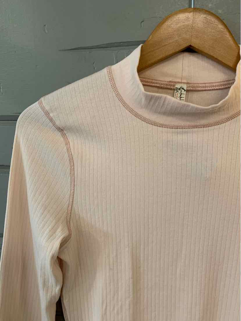 Light pink ribbed long-sleeve mock neck top hanging on wooden hanger.