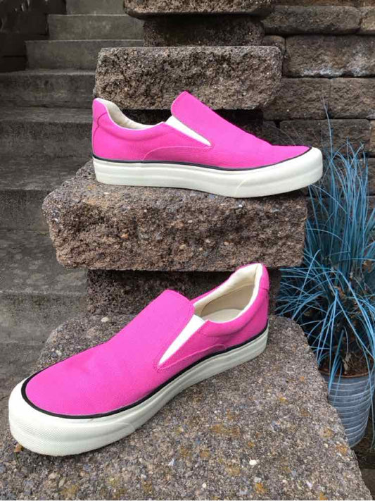 Pink slip-on sneakers with white soles and elastic side panels on textured stone steps.