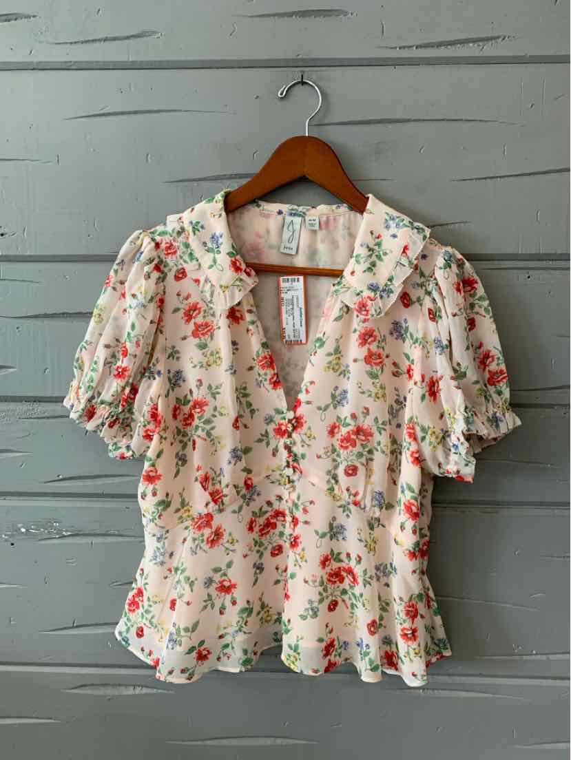 Light pink floral blouse with puff sleeves and a ruffled collar on wooden hanger.