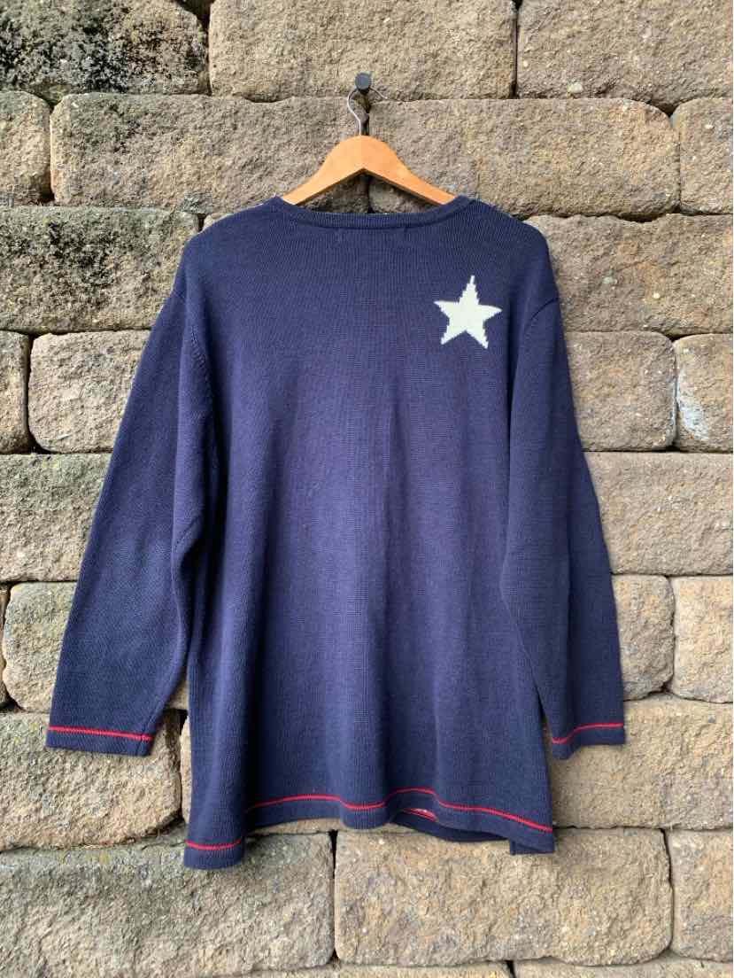 Navy blue long-sleeve knit tunic with a white star on the upper chest and red trim along the hem and cuffs.