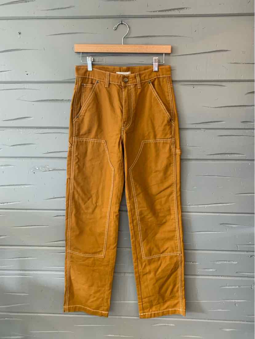 Mustard yellow high-waisted pants with front patch pockets and visible seam detailing.