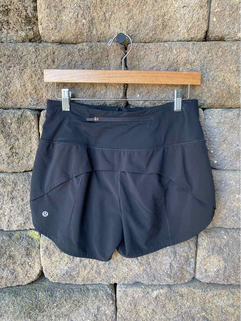 Black athletic shorts with curved hem and wide waistband, featuring subtle Lululemon logo on left leg.