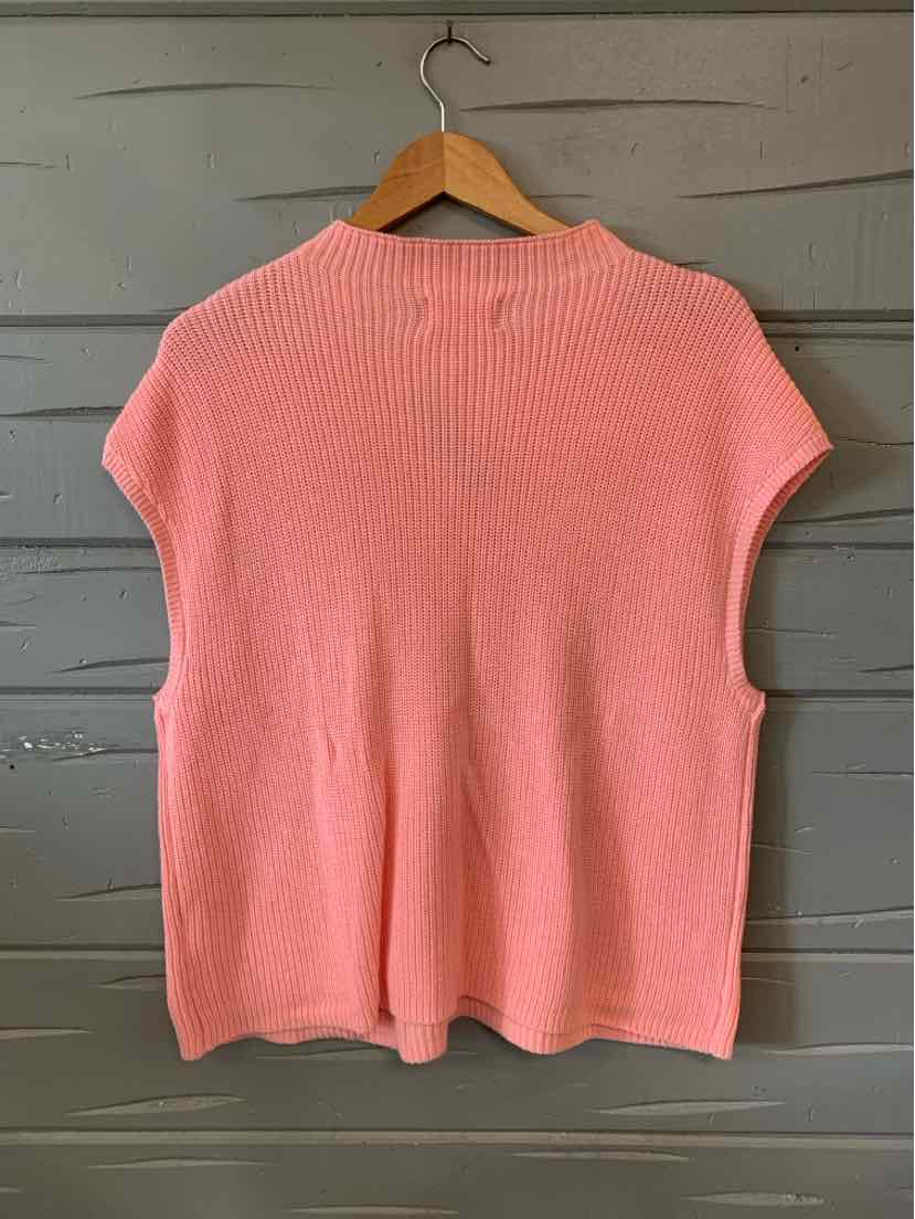 Pink knit short-sleeve sweater with ribbed neckline and loose fit on wooden hanger.