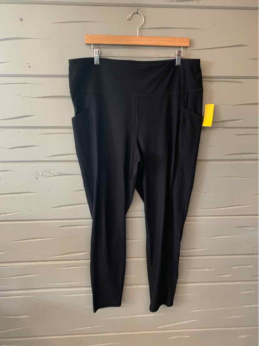 Black high-waist solid leggings with ankle length, hanging on wooden hanger against gray wall.