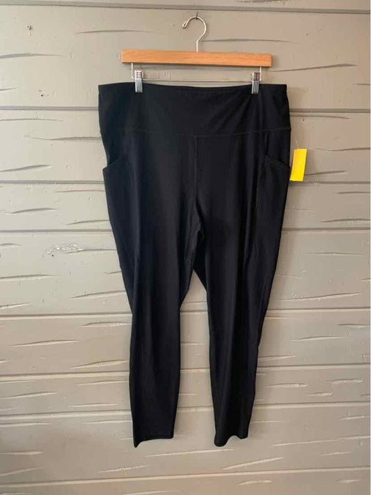 Black high-waist solid leggings with ankle length, hanging on wooden hanger against gray wall.
