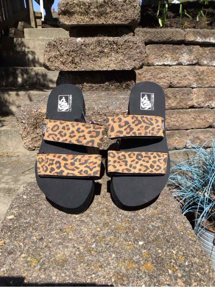 Tan Vans sandals with black soles and leopard print double straps, size 6.