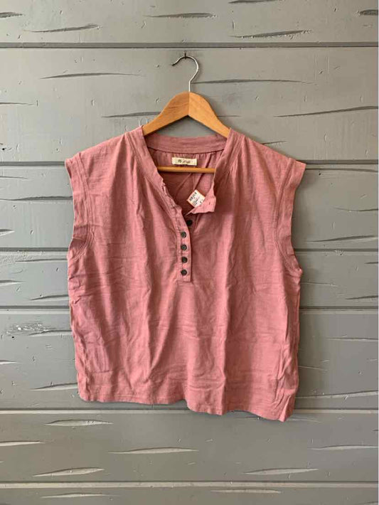 Sleeveless mauve linen blouse with buttoned v-neck and relaxed fit on wooden hanger.