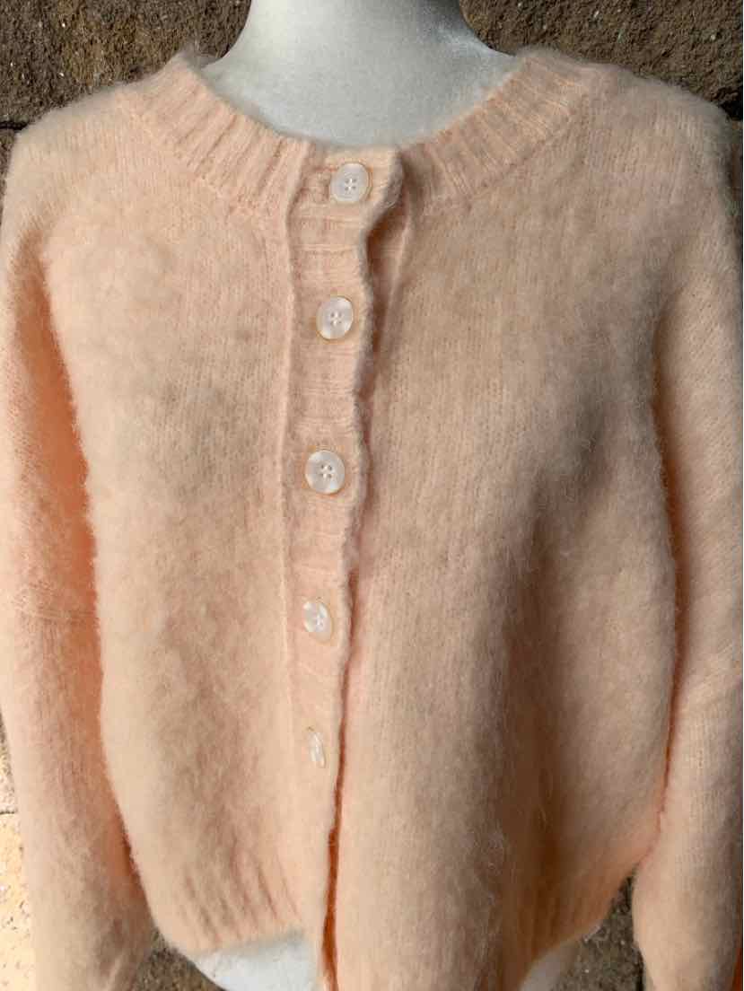 Pale peach fuzzy knit cardigan with a round neckline, button front, and long sleeves.