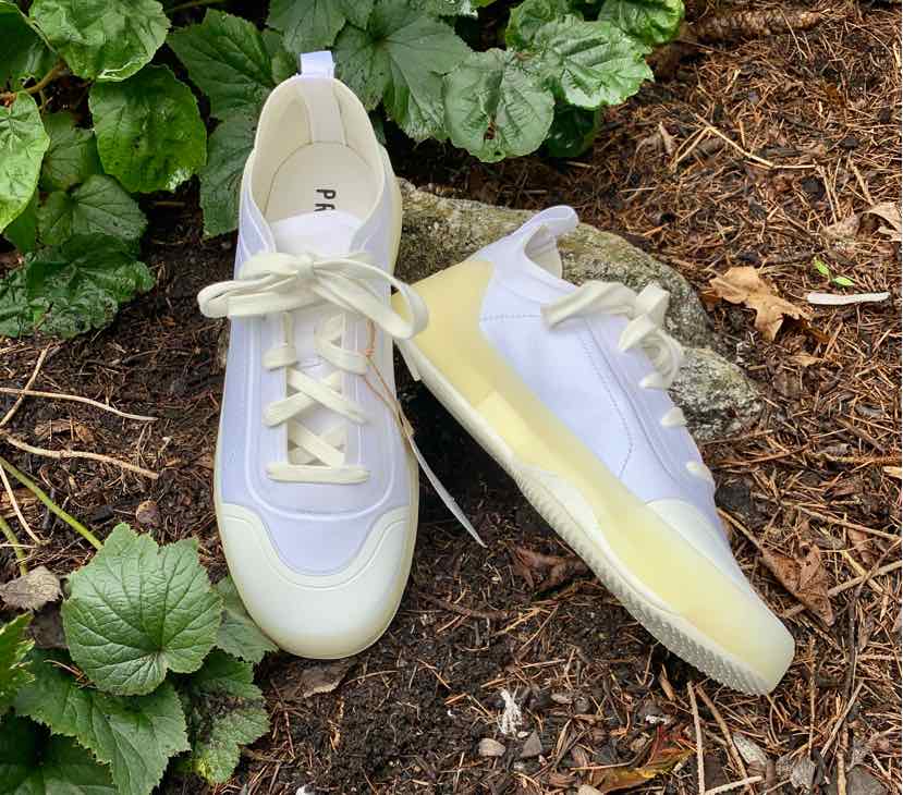 White low-top Adidas sneakers with cream sole, lace-up front, and minimalist design.