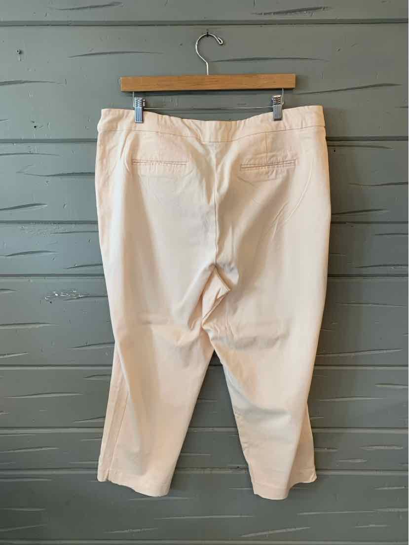 White cropped pants with back pockets and belt loops hanging on wooden hanger.