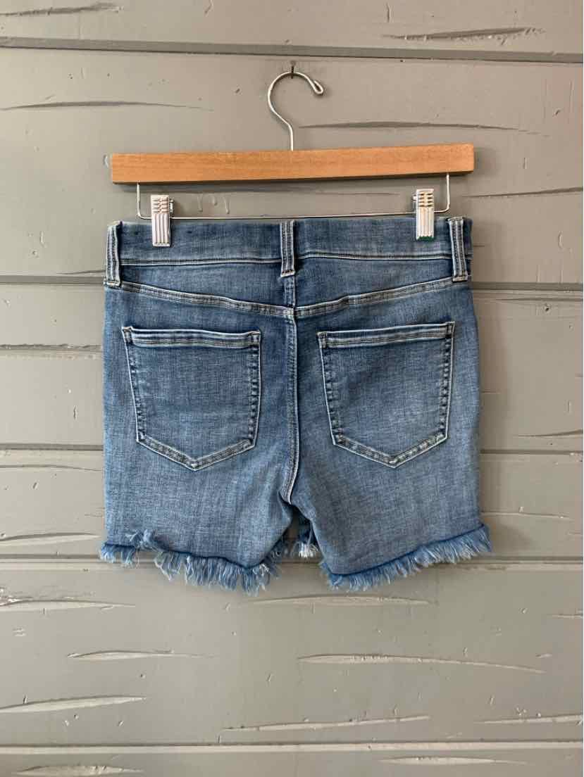 Light blue denim shorts with frayed hems and two back patch pockets hanging on wooden hanger.
