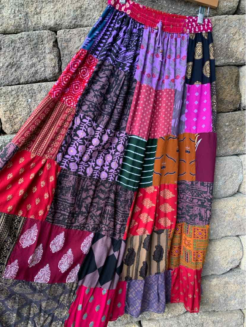 Flowing multicolor patchwork skirt with vibrant floral, geometric, and paisley prints in red, purple, pink, and orange.