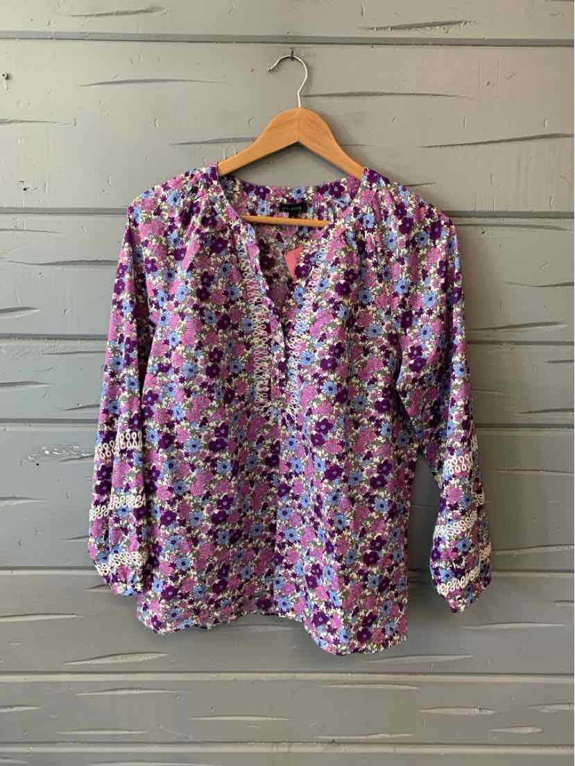 Long-sleeve floral blouse in purple, pink, and white with a V-neck and gathered cuffs.
